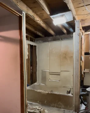Bathroom demolition with tub in place and ceiling and wall finishes removed
