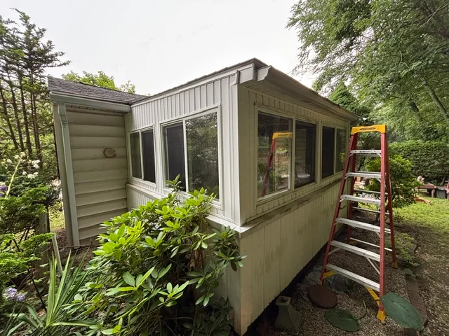 Enclosed three-season room at the back of a yellow house before removal